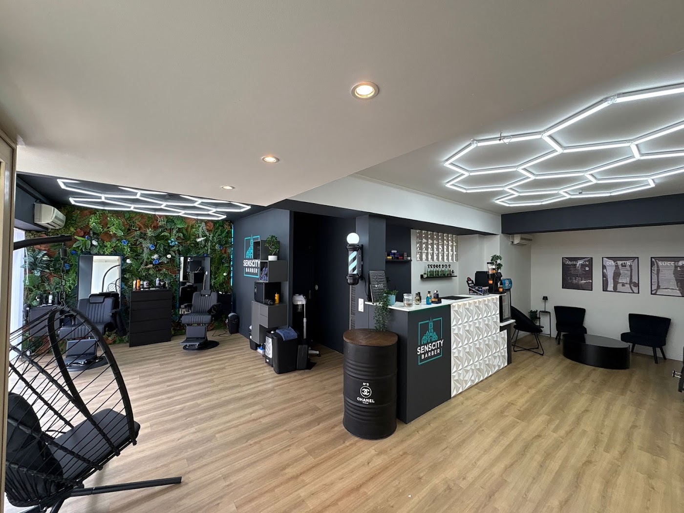 Les fauteuils de barbier devant le mur végétal et le comptoir du salon